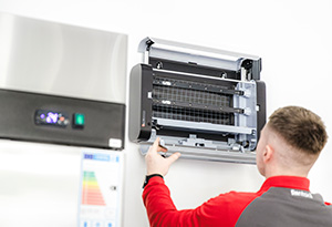 A fly control expert installs a Lumnia electronic UV fly trap in a restaurant kitchen